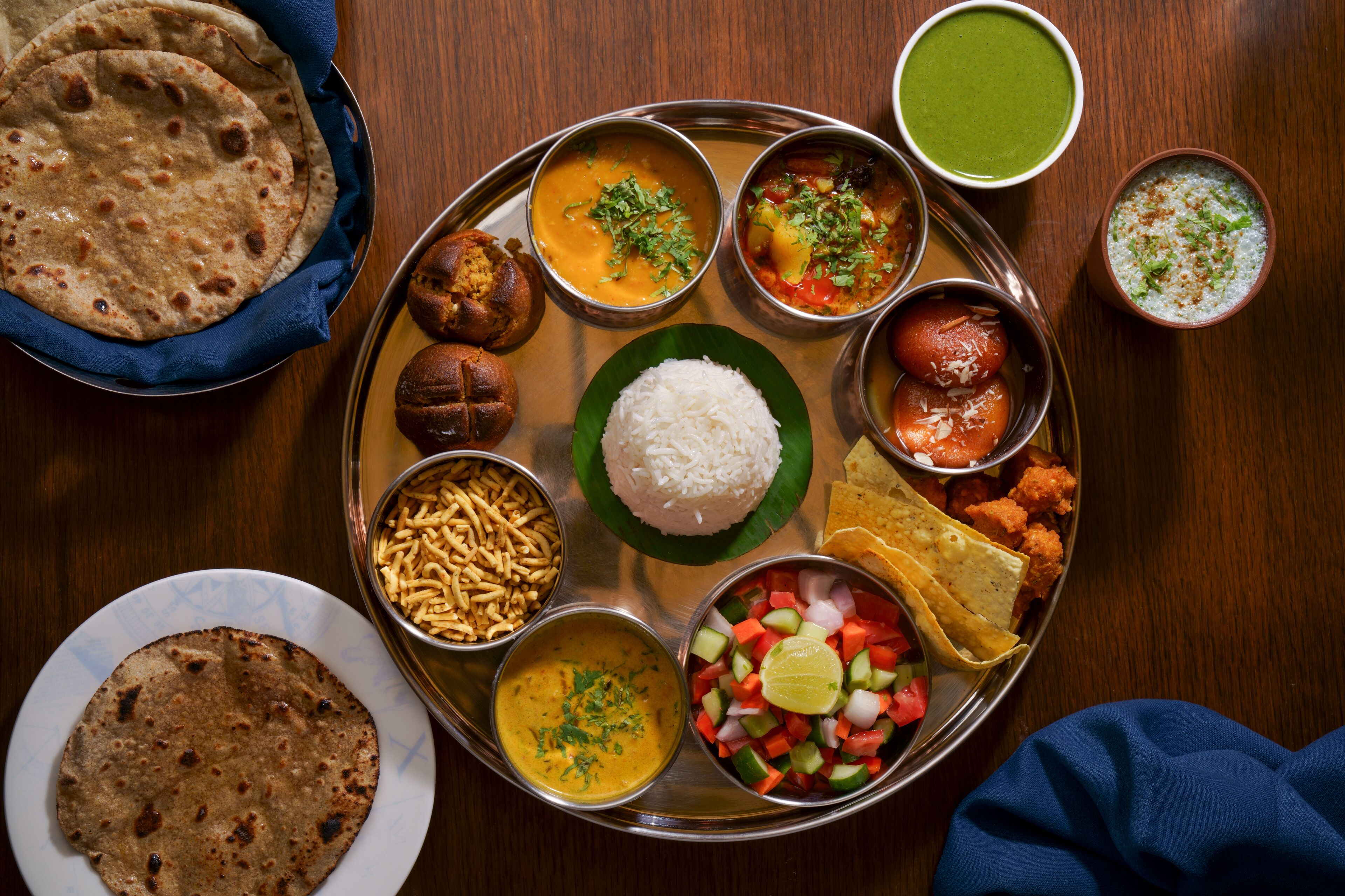 A traditional Indian meal with various dishes including rice, flatbreads, and a variety of curries and snacks.