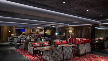 A modern lounge area with sofas and armchairs, a bar, and a seating area with a patterned carpet.