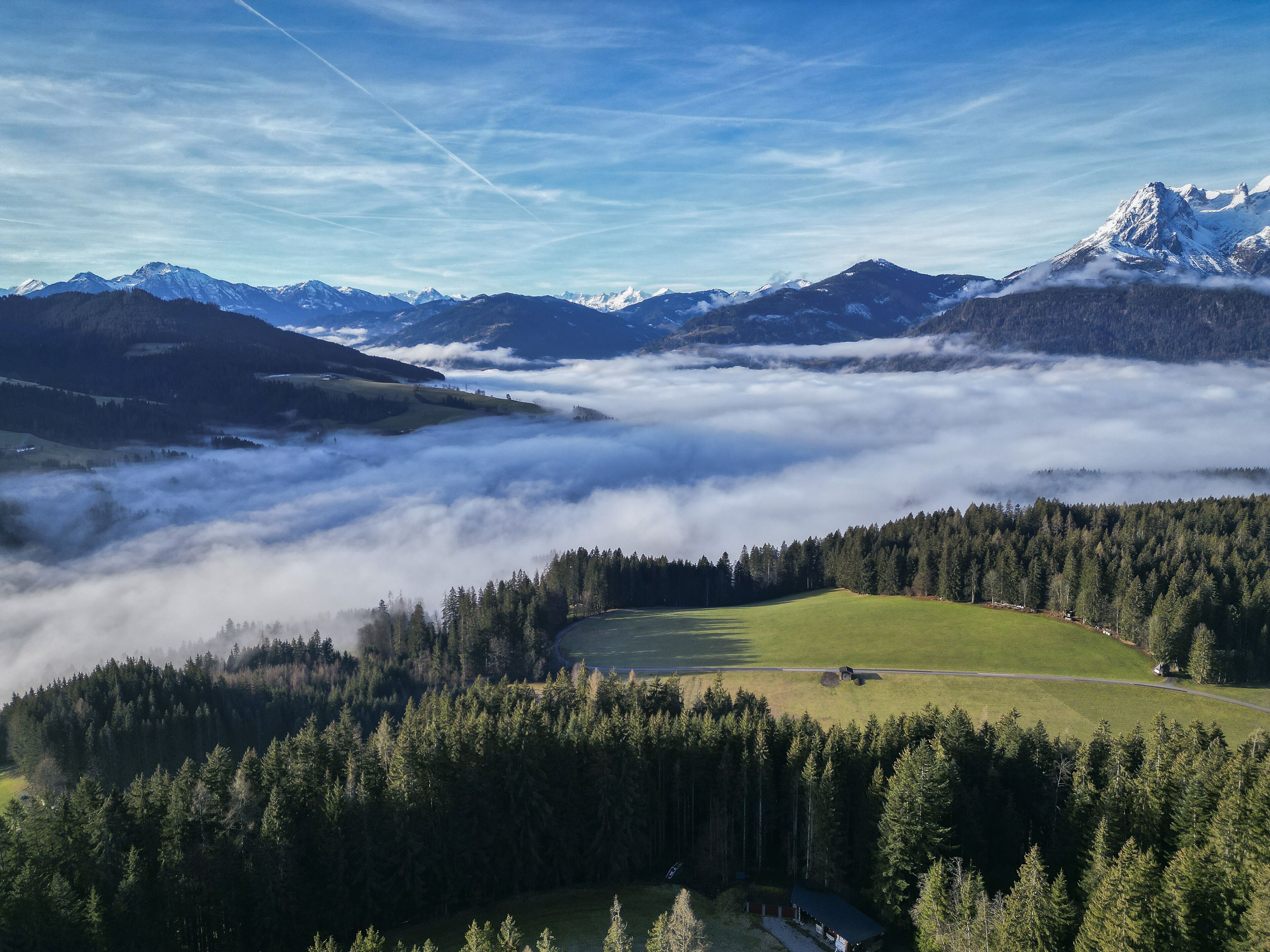 A mountainous landscape with a valley, forested area, and a small building.