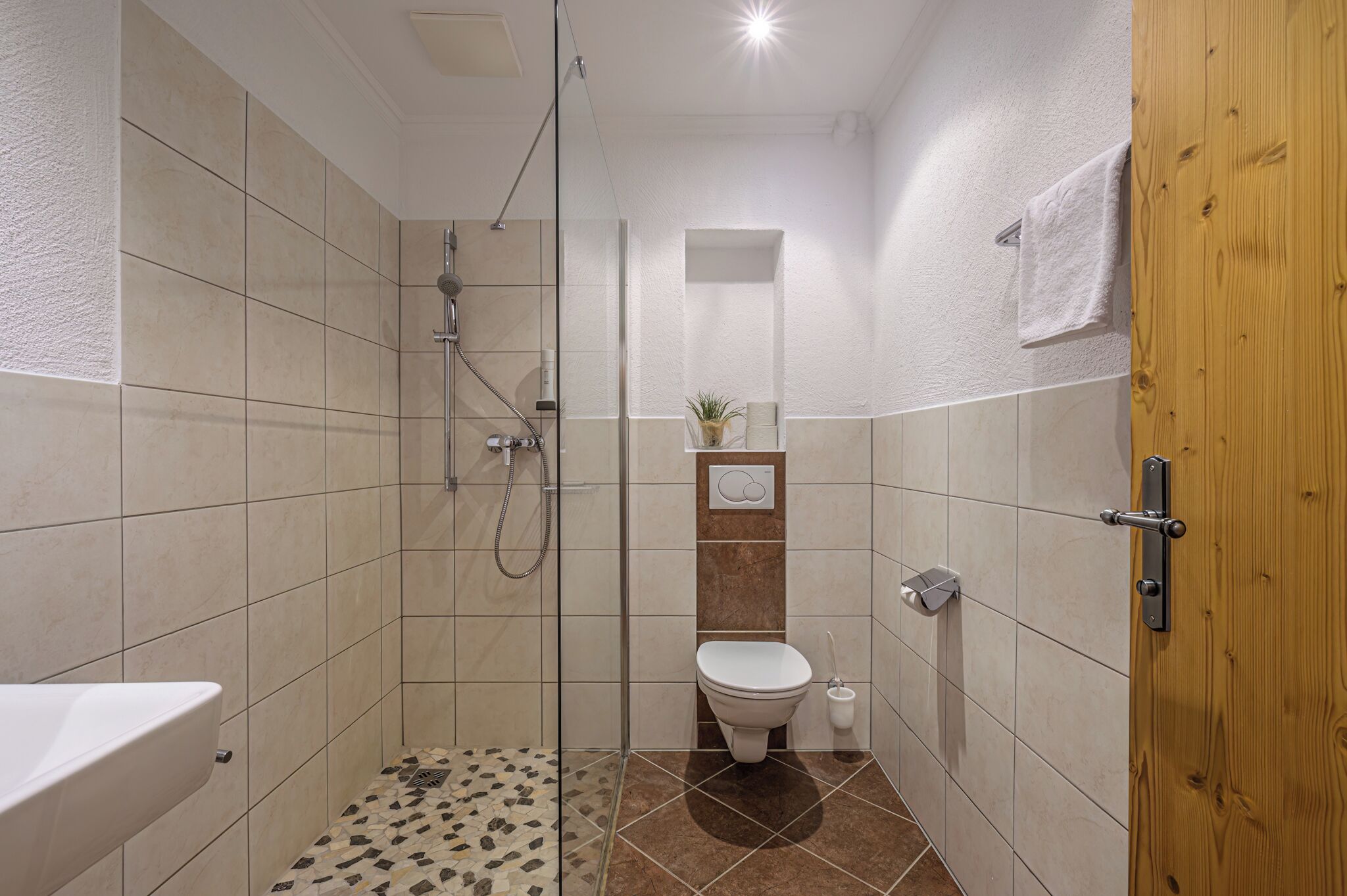A modern bathroom with a shower, toilet, and sink.