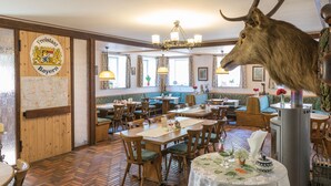 Un restaurante con muebles de madera, una cabeza de ciervo montada y un mapa en la pared.