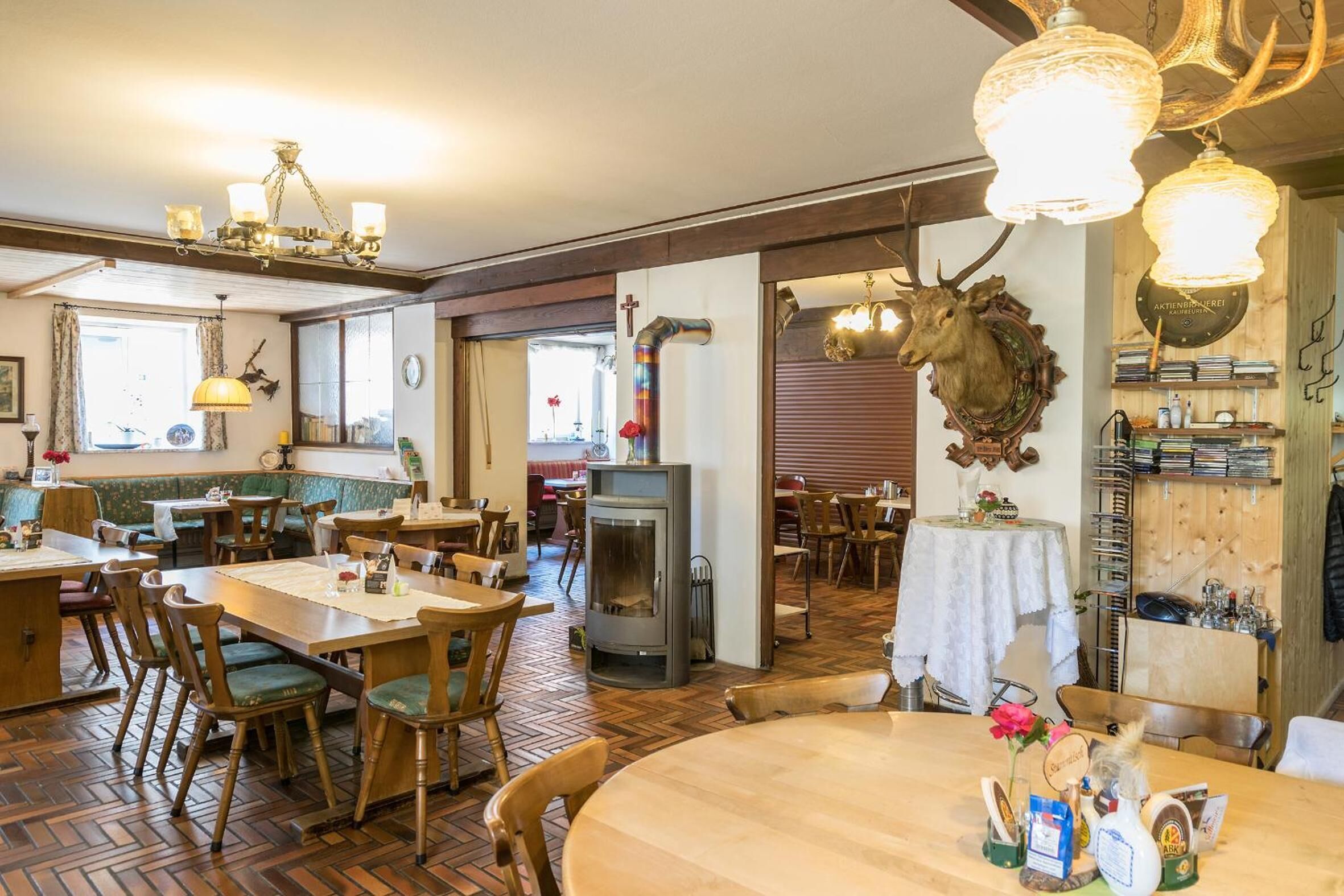 Un restaurant avec des meubles en bois, une cheminée et une tête de cerf décorative.