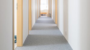 Un pasillo largo y estrecho con suelos alfombrados y puertas de madera a ambos lados.