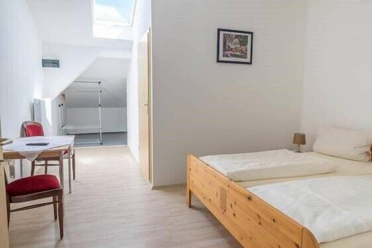 Una habitación con una cama de madera, un escritorio con una silla y una ventana.