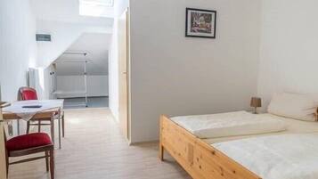 A room with a wooden bed, a desk with a chair, and a window.