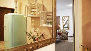 Una habitación con un refrigerador azul claro, un espejo con marco decorativo y un arreglo floral.
