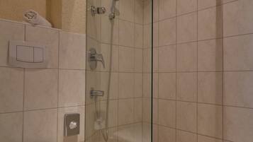 Un baño con inodoro, ducha con puerta de vidrio y secamanos.
