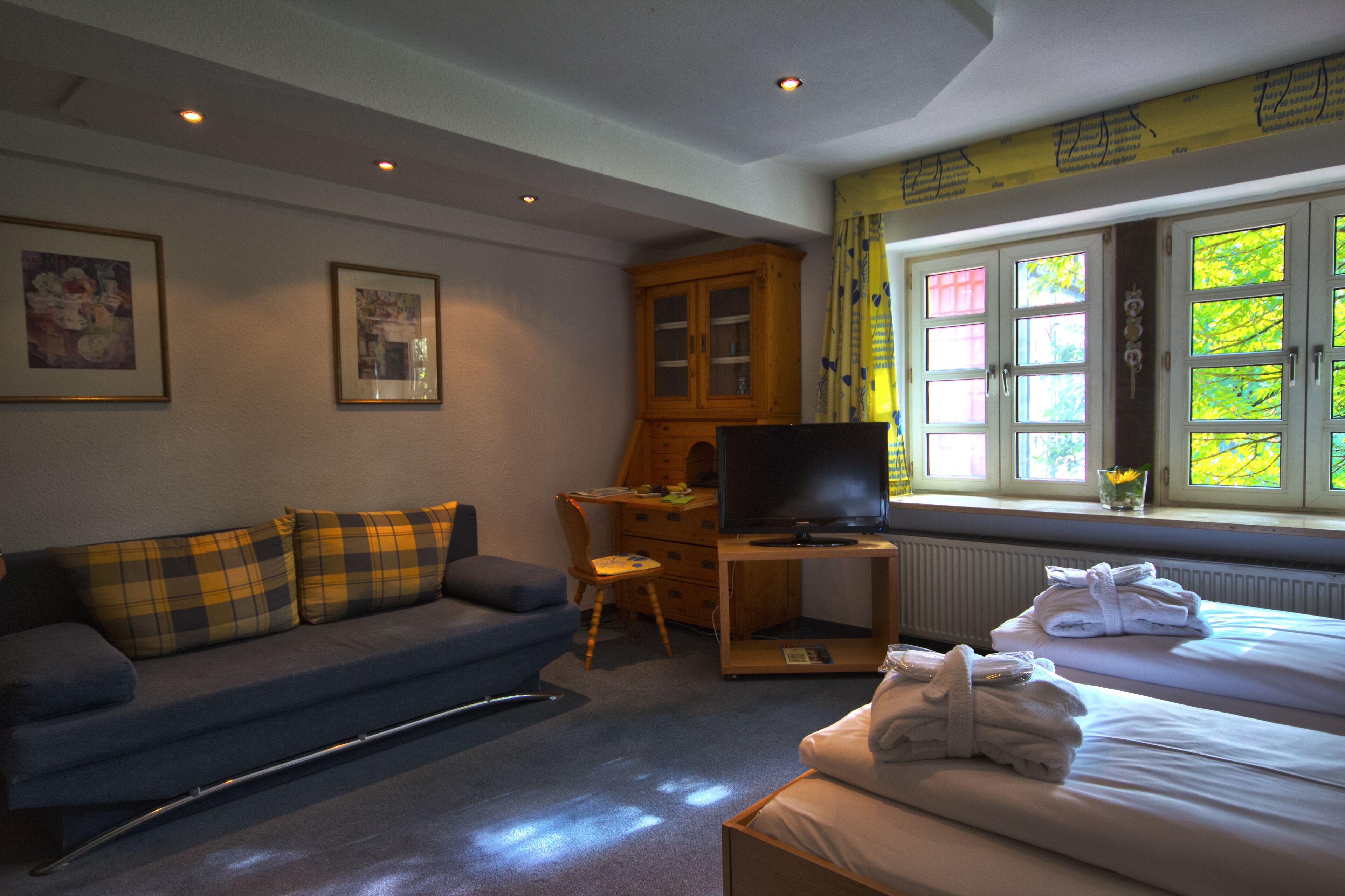 Une chambre d’hôtel équipée d’un canapé, d’une télévision, d’un bureau et d’un lit avec des serviettes.