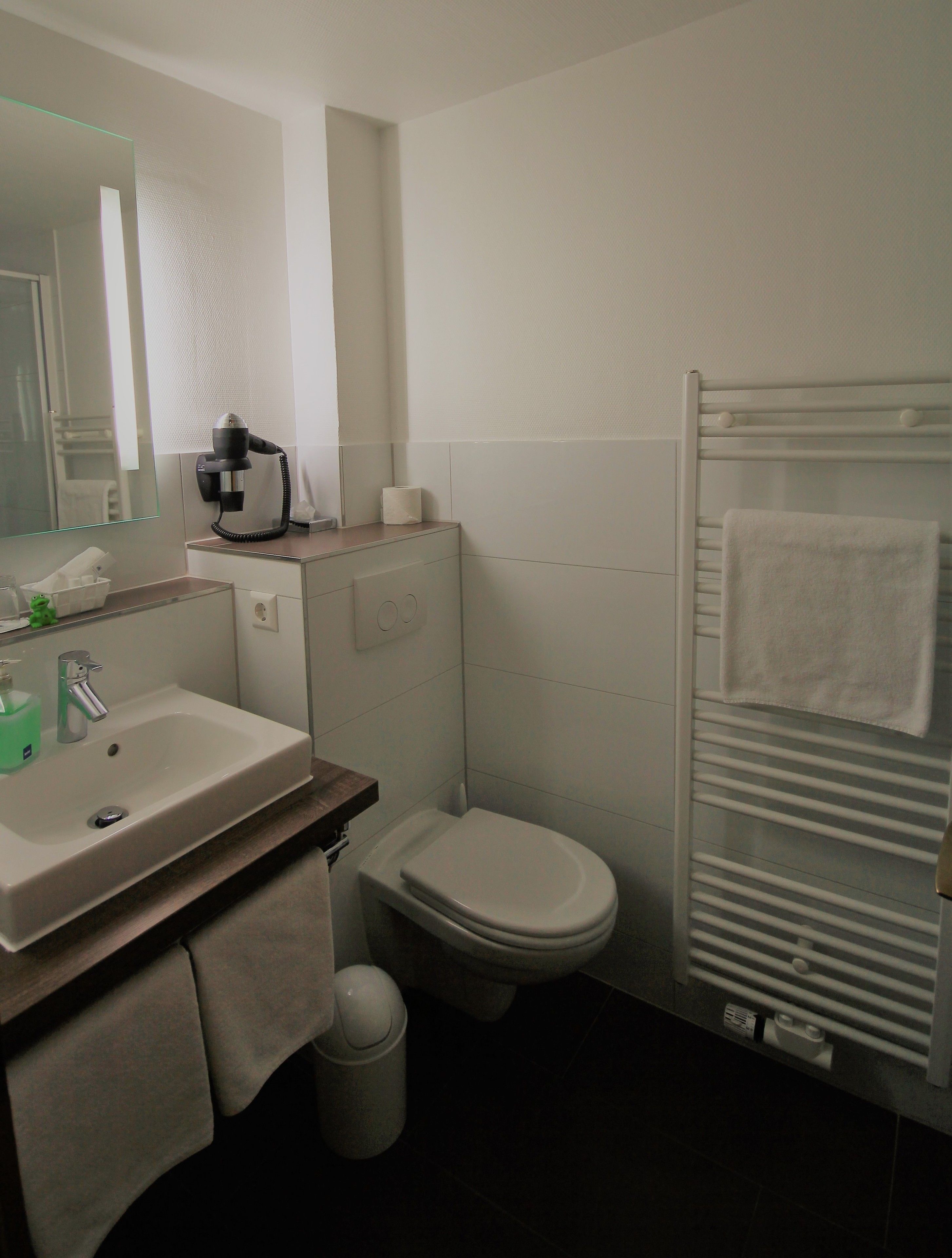 A compact bathroom with a sink, toilet, and towel rack.