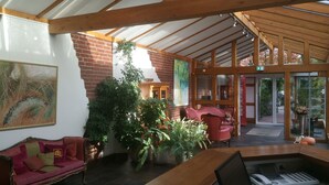 Ein gemütliches Interieur mit einer roten Backsteinwand, einem großen Gemälde, einer Holzbalkendecke und einer Sitzecke mit einem roten Sofa und einem Tisch.
