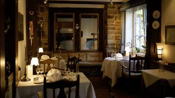 A cozy dining area with stone walls, wooden furniture, and tables set for a meal.