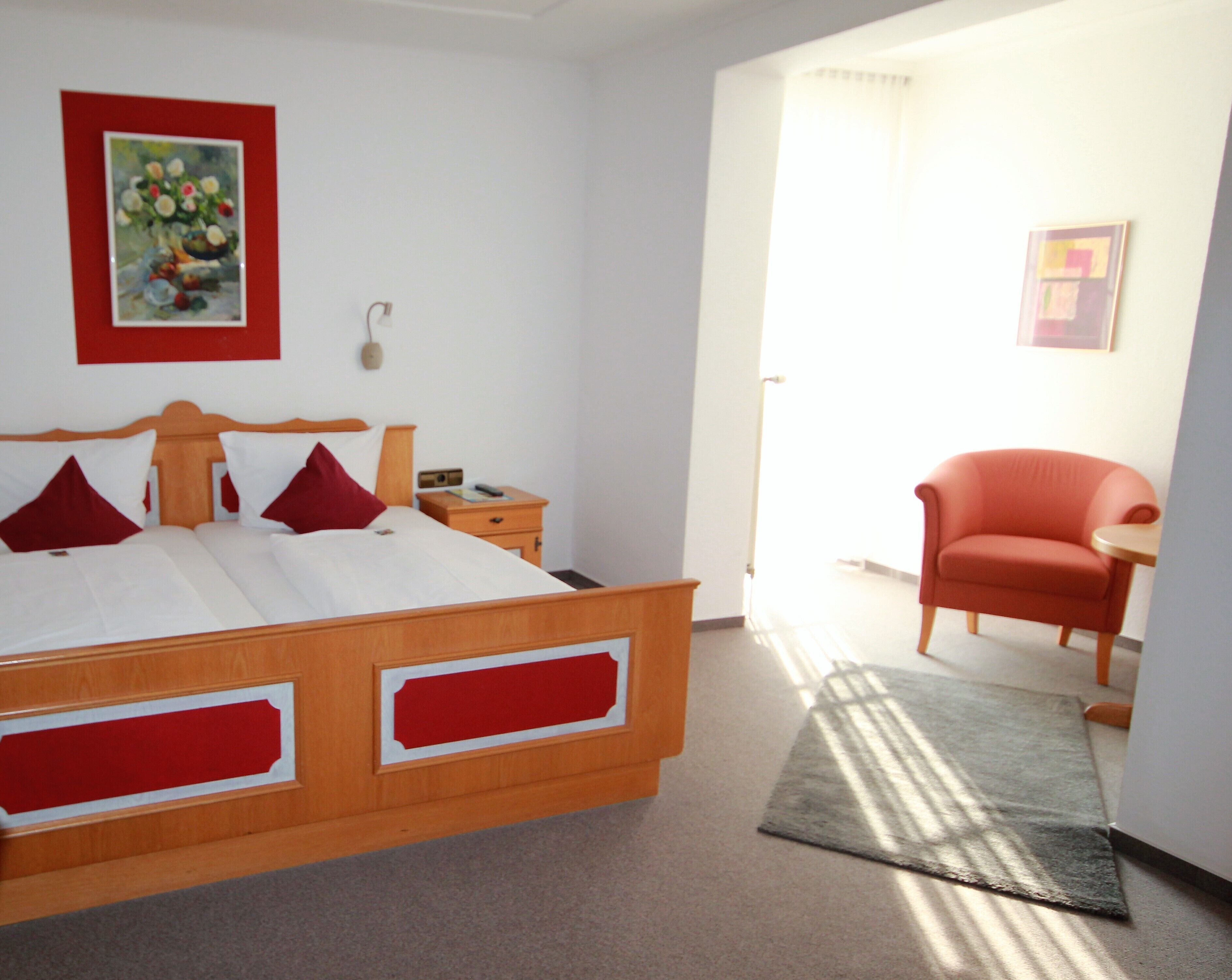 Un dormitorio con una cama de madera, una mesita de noche, una silla y un cuadro en la pared.