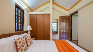 A hotel room with a large bed, wooden wardrobe, and a window with curtains. - Mistral Holidays (Benaulim)