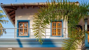A two-story building with a balcony, a glass door entrance, and a stone pathway with grass inlays. - Mistral Holidays (Benaulim)