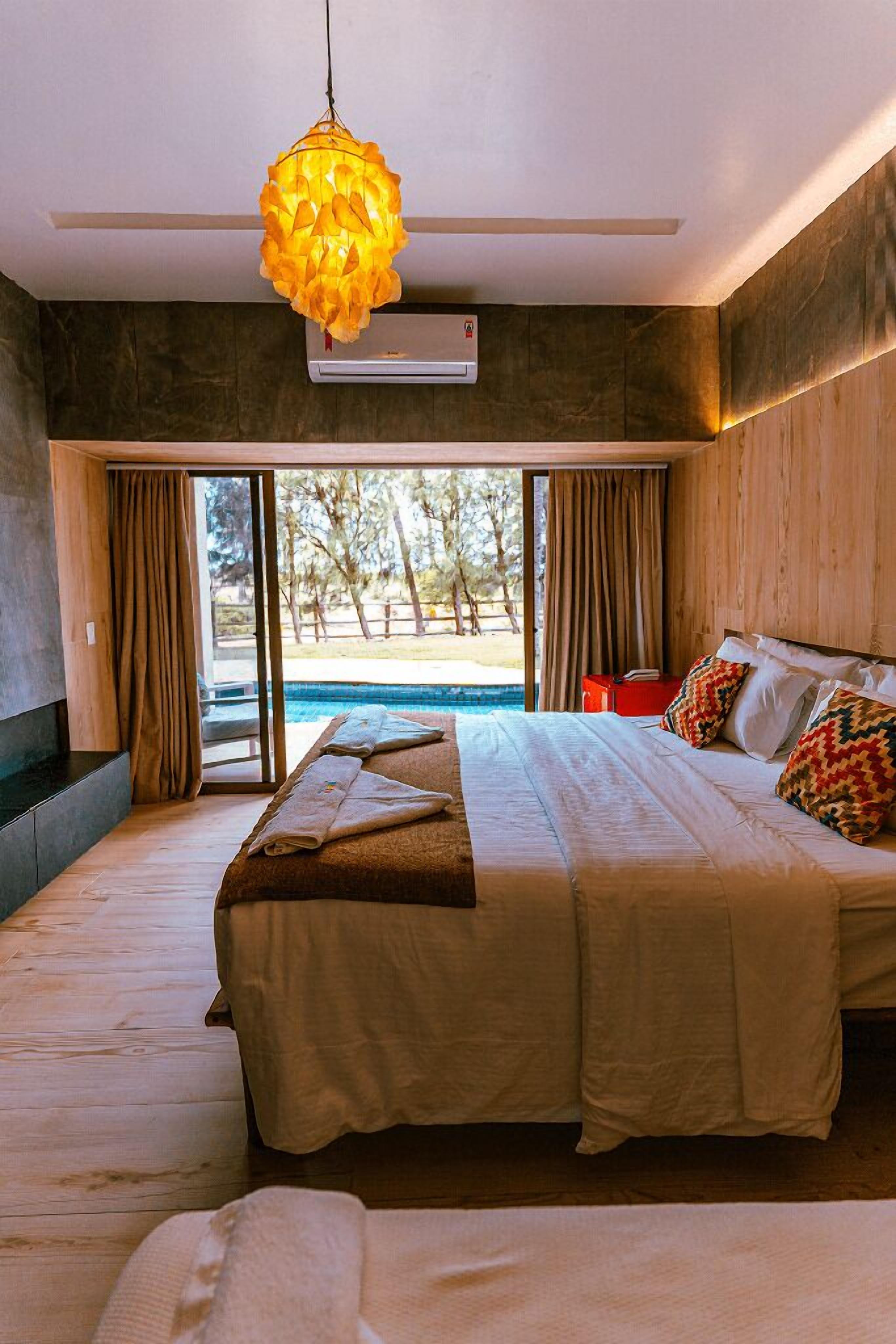 Una cama grande con vista a una piscina y árboles.
