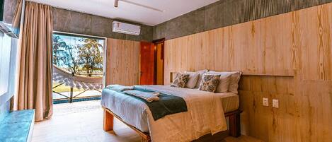 A modern bedroom with a large bed, wooden panel walls, and a view of the outdoors.