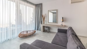 Un salon moderne avec un canapé gris, une table basse en osier et une petite table d’appoint avec une lampe.