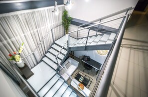 Un intérieur moderne avec un escalier, un canapé, une table basse et une plante.