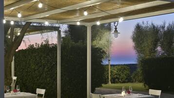Una terrazza esterna con tavoli apparecchiati per consumare pasti, immersa nel verde e con vista sul paesaggio.