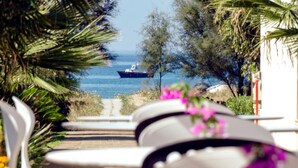 A view of a boat on the water, a pathway leading to outdoor seating, and surrounding greenery. - Paestum Inn Beach Resort (Capaccio-Paestum)