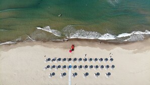 An aerial view of a beach with rows of umbrellas and lounge chairs, a sandy shore, and gentle waves. - Paestum Inn Beach Resort (Capaccio-Paestum)