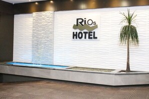 A reception area with a wavy wall design, a water feature, and a palm tree.