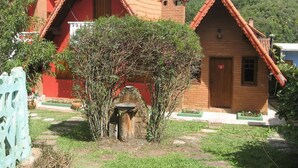 Een rij traditionele huisjes met rode daken, bakstenen muren, een stenen waterput en een kleine tuin.