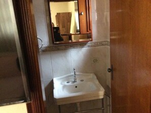 A bathroom with a white sink, a mirror above it, and a wooden cabinet.