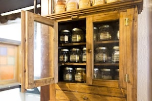 A wooden cabinet with glass doors containing various jars labeled with names like "Cinnamon" and "Cinnamon." - Villa da Vila (Camanducaia)