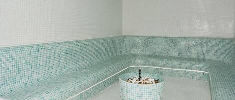 Une salle de spa dotée d’un espace détente aux lignes courbes et d’une petite fontaine.