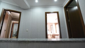 Une chambre d’hôtel aux couleurs neutres, dotée d’un comptoir en granit et offrant une vue sur la chambre voisine.