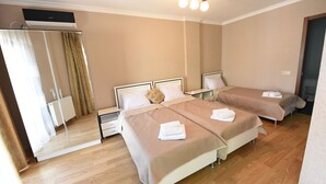 Une chambre d’hôtel avec deux lits, un grand miroir, un luminaire au plafond et un plancher en bois.