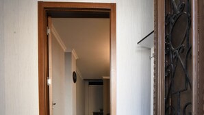 Un couloir avec une porte en bois et un escalier menant à une autre pièce.