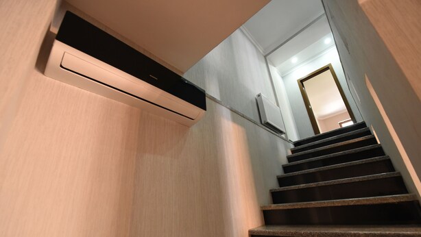 Un escalier moderne avec une rampe, menant à une pièce dont la porte se trouve en haut.