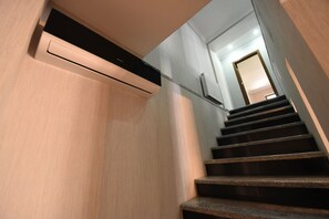 A modern staircase with a handrail, leading to a room with a door at the top.