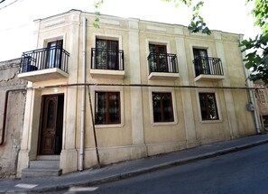 A multi-story building with balconies, a wooden door, and a visible utility pole. - New House in Old Tbilisi  (Tbilisi)