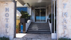 Η είσοδος ενός ξενοδοχείου με πέτρινους τοίχους, μια σκάλα και μια πινακίδα που υποδεικνύει το όνομα του ξενοδοχείου.