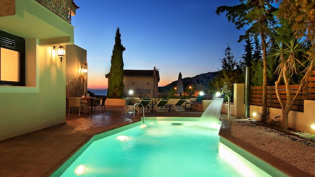 Una piscina con tobogán de agua, sillas de descanso y vistas al atardecer.