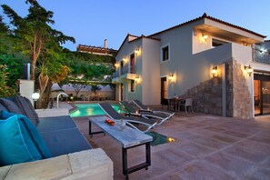 Una casa moderna con piscina, area salotto esterna e pareti in pietra.