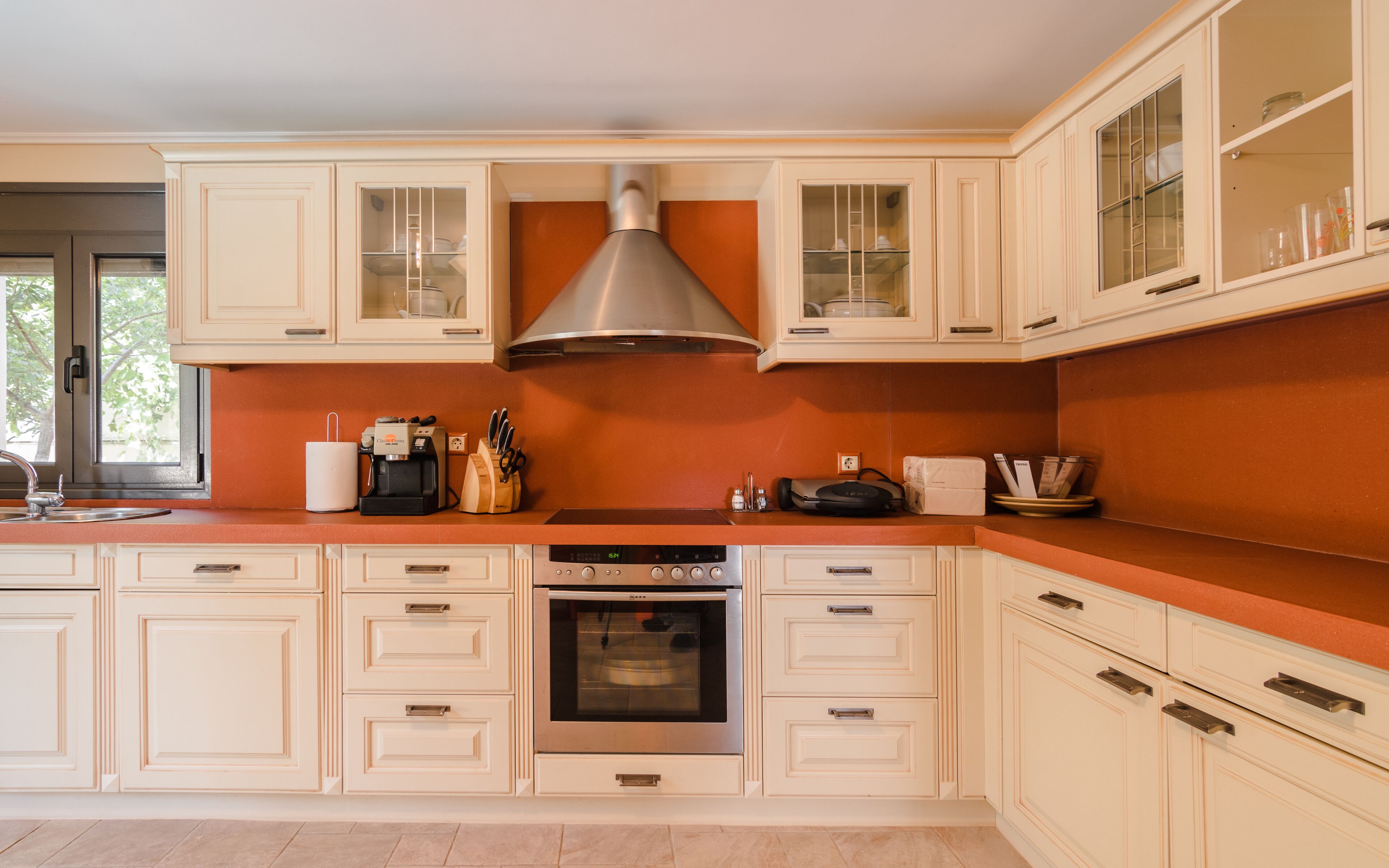 A modern kitchen with white cabinetry, a stainless steel range hood, and a built-in oven.