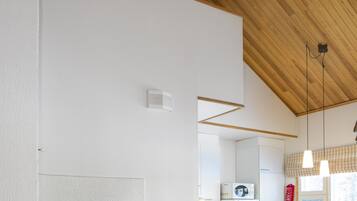 A modern kitchen with a built-in microwave, a dining area with wooden chairs, and a fireplace with a visible fire.