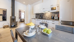 A modern kitchen with white cabinets, a black stove, and a dining area with a wooden table set for a meal.