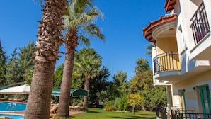 A resort with a pool, palm trees, and a white building with balconies. - Rebin Beach Hotel (Fethiye)