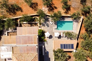 An aerial view of a property with a swimming pool, solar panels, and a covered patio area. - Lithos Guesthouse Kardamili (West Mani)
