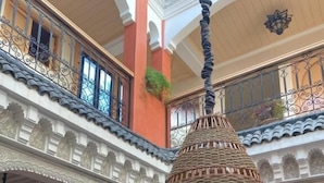 A multi-level interior with ornate arches, a hanging woven light fixture, and a staircase with metal railings. - Riad Dar Nakhla (Marrakech)