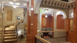 A staircase with ornate railings and a wooden finish, leading to a room with a patterned bench and a door. - Riad Dar Nakhla (Marrakech)