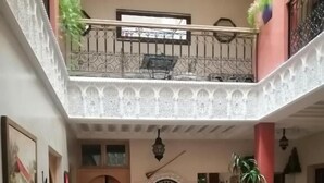 A dining area with a high ceiling, a central table with chairs, and a decorative door. - Riad Dar Nakhla (Marrakech)