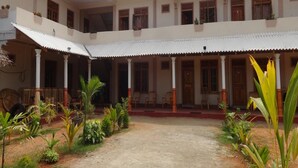 A two-story building with a central courtyard, featuring a covered walkway and a variety of plants. - Hotel Alas Garden (Trincomalee)
