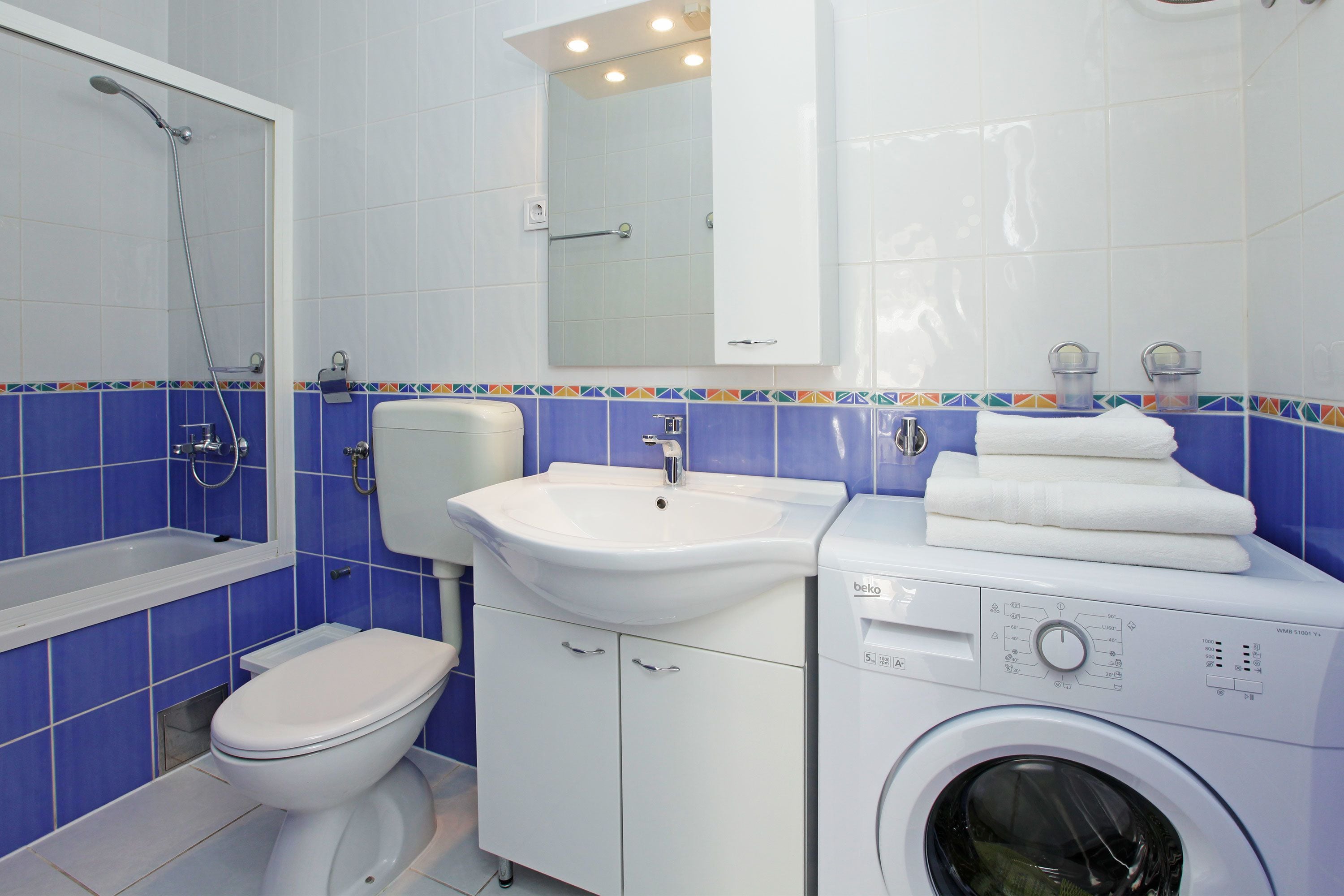 A bathroom with a toilet, sink, and washing machine.