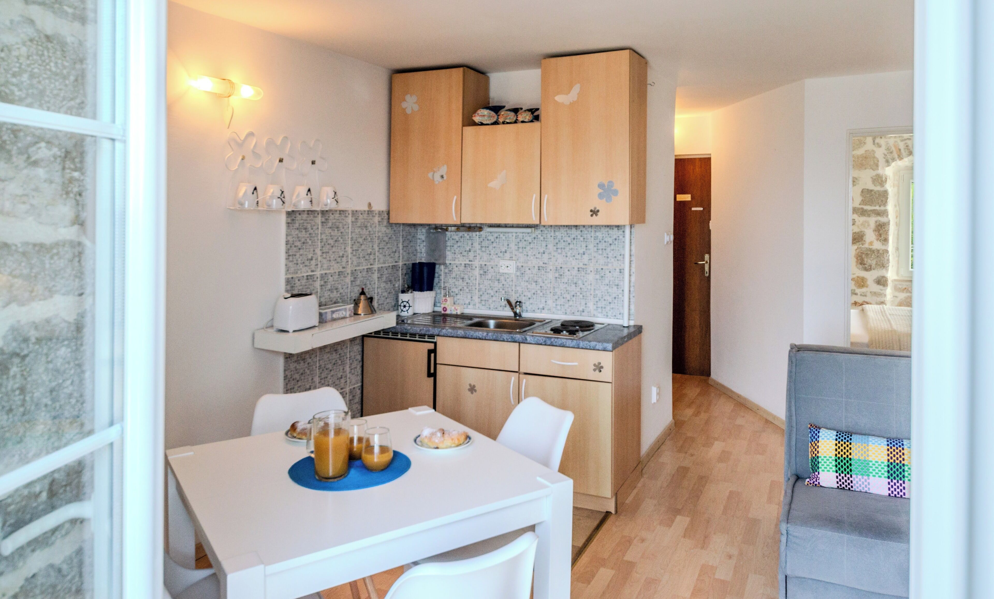 A compact kitchen with wooden cabinets, a white countertop, and a dining area with a table and chairs.